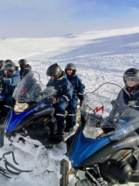 Guests riding snowmobiles in snowy landscape near Gullfoss waterfall, Iceland.