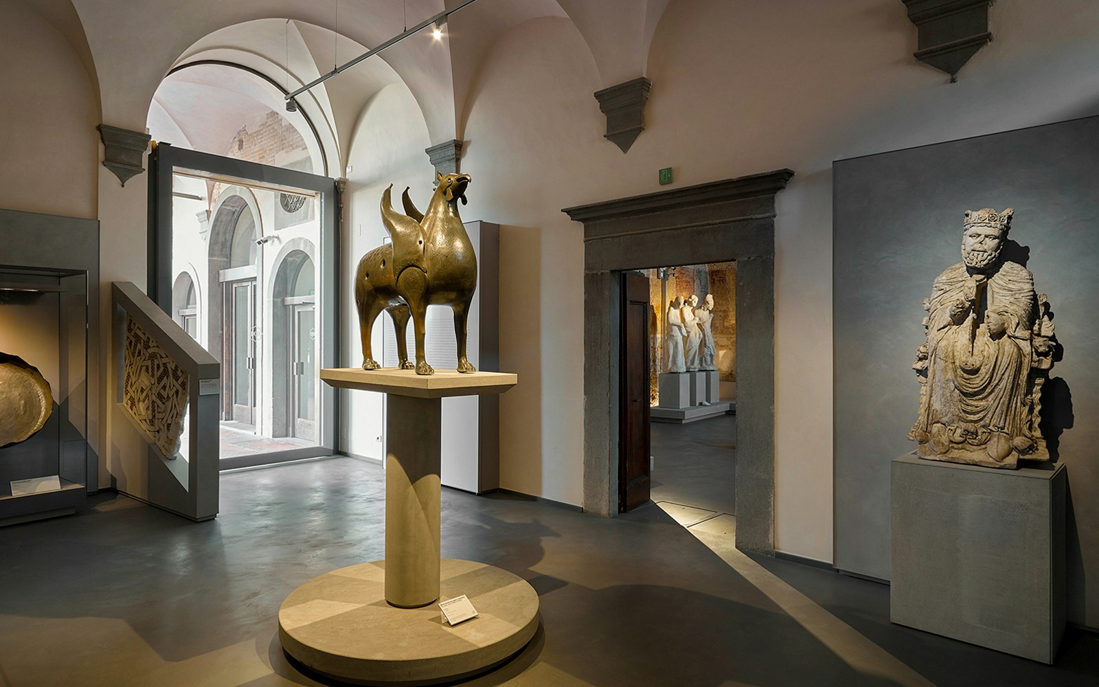 Sculptures displayed at Opera del Duomo Museum in Pisa, featuring a bronze griffin and stone figures.