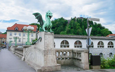 Dragon Bridge statue with Ljubljana Castle in the background, Slovenia.