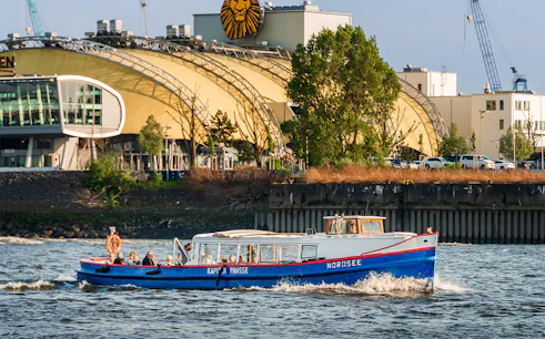 Boat on Hamburg harbor tour passing theater building.
