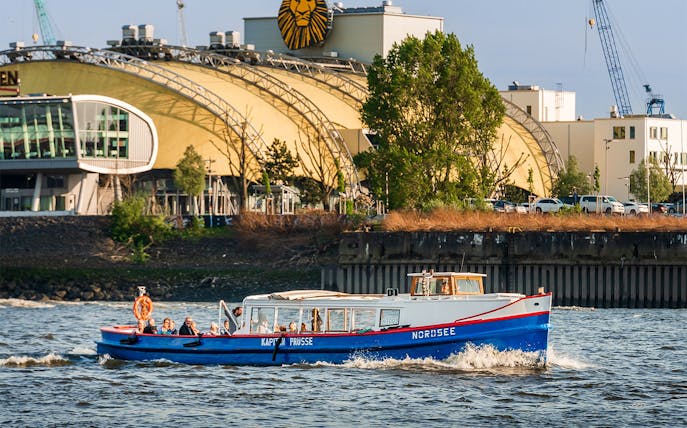 Boat on Hamburg harbor tour passing theater building.