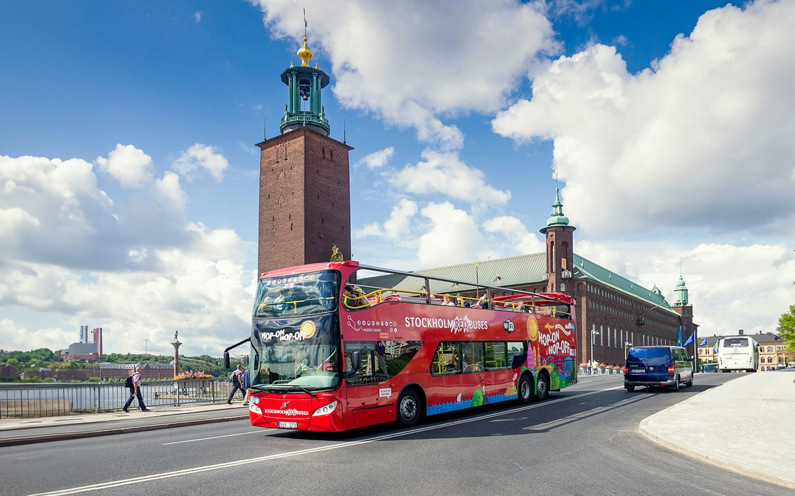Stockholm hop-on hop-off red bus near Royal Palace with tourists exploring city.