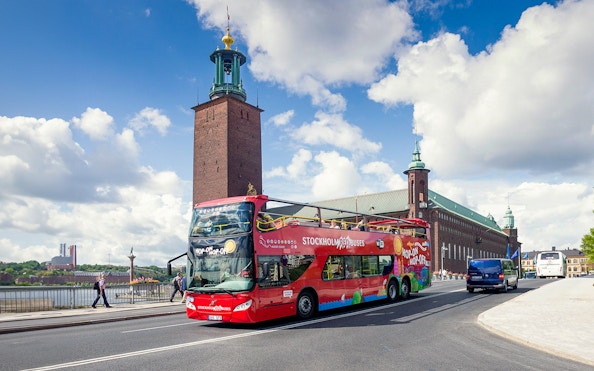 Red hop-on hop-off bus in front of Stockholm City Hall.