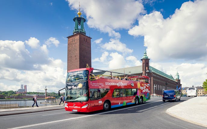 Red hop-on hop-off bus in front of Stockholm City Hall.