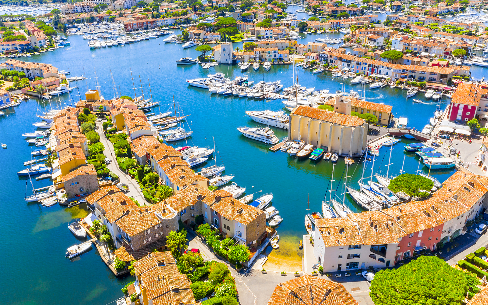 Aerial view of Port Grimaud with boats docked along canals and colorful buildings.