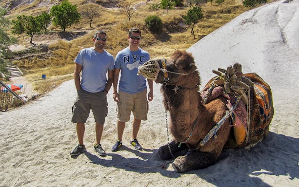 Guided camel ride in Cappadocia with two tourists and a resting camel.