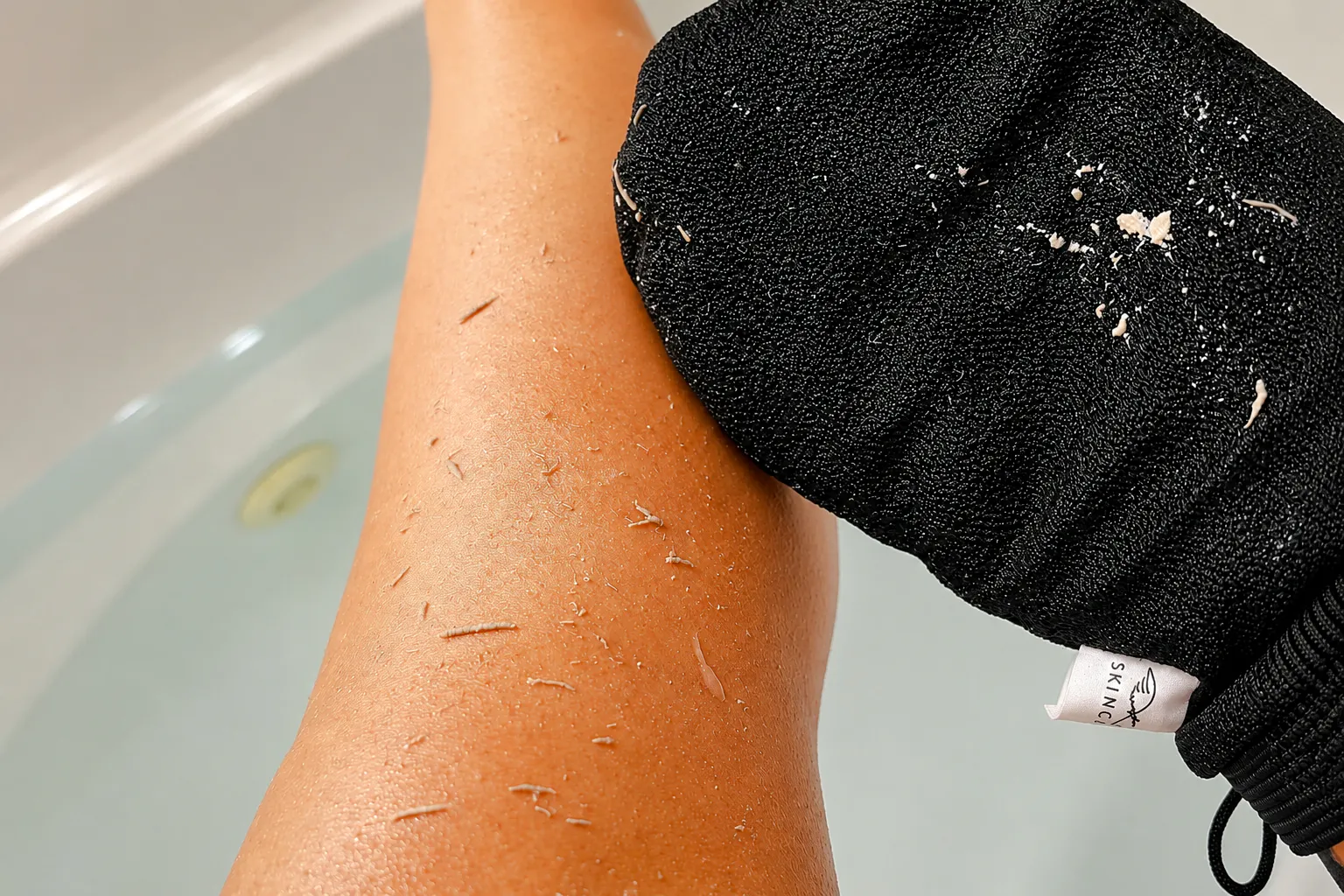 Exfoliating glove scrubbing leg during Moroccan hammam experience in Marrakech.