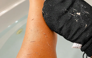 Exfoliating glove scrubbing leg during Moroccan hammam experience in Marrakech.