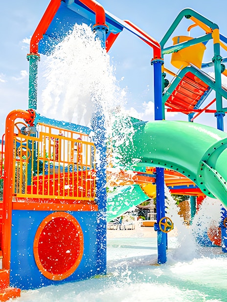 Child playing at the colorful water playground in zona infantil at Aquopolis.