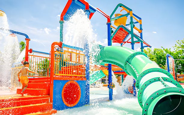 Child playing at the colorful water playground in zona infantil at Aquopolis.