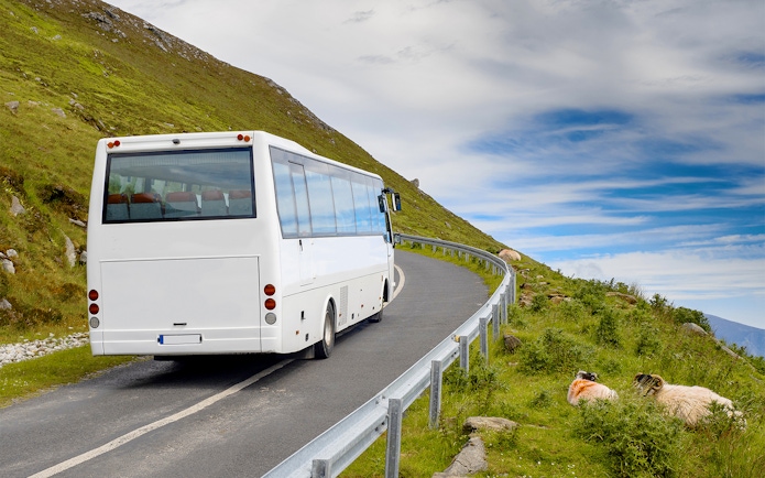 Airconditioned coach on winding road through lush Irish countryside.