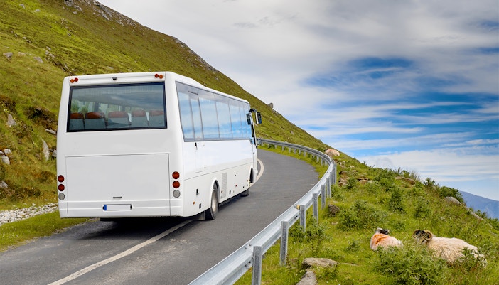 Airconditioned coach on winding road through lush Irish countryside.