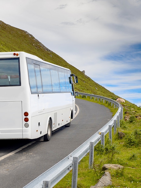 Airconditioned coach on winding road through lush Irish countryside.