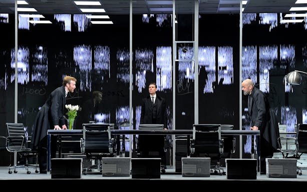 Three actors in a modern office setting during a scene from The Lehman Trilogy.