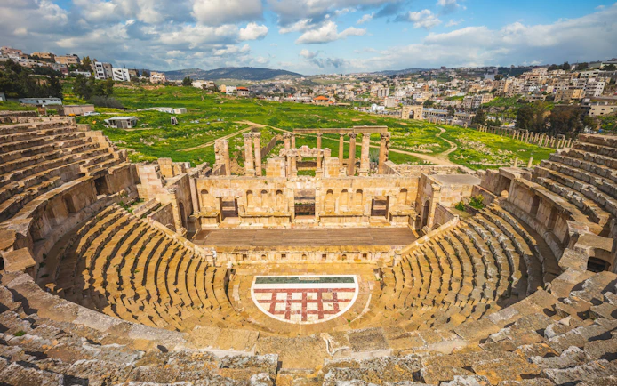 Roman Theatre in Jerash with cityscape, near Amman, Jordan.