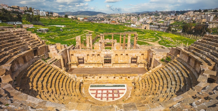 Roman Theatre in Jerash with cityscape, near Amman, Jordan.