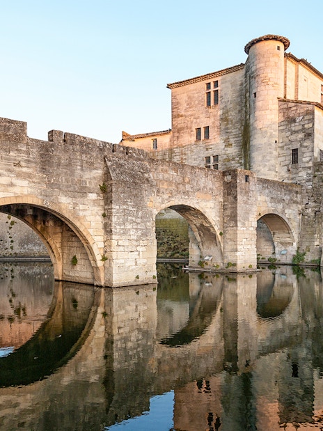 Towers and ramparts of Aigues-Mortes reflected in water, France.