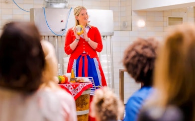 Cheese making demonstration in Edam with a guide holding a cheese wheel.