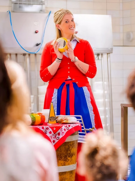 Cheese making demonstration in Edam with a guide holding a cheese wheel.