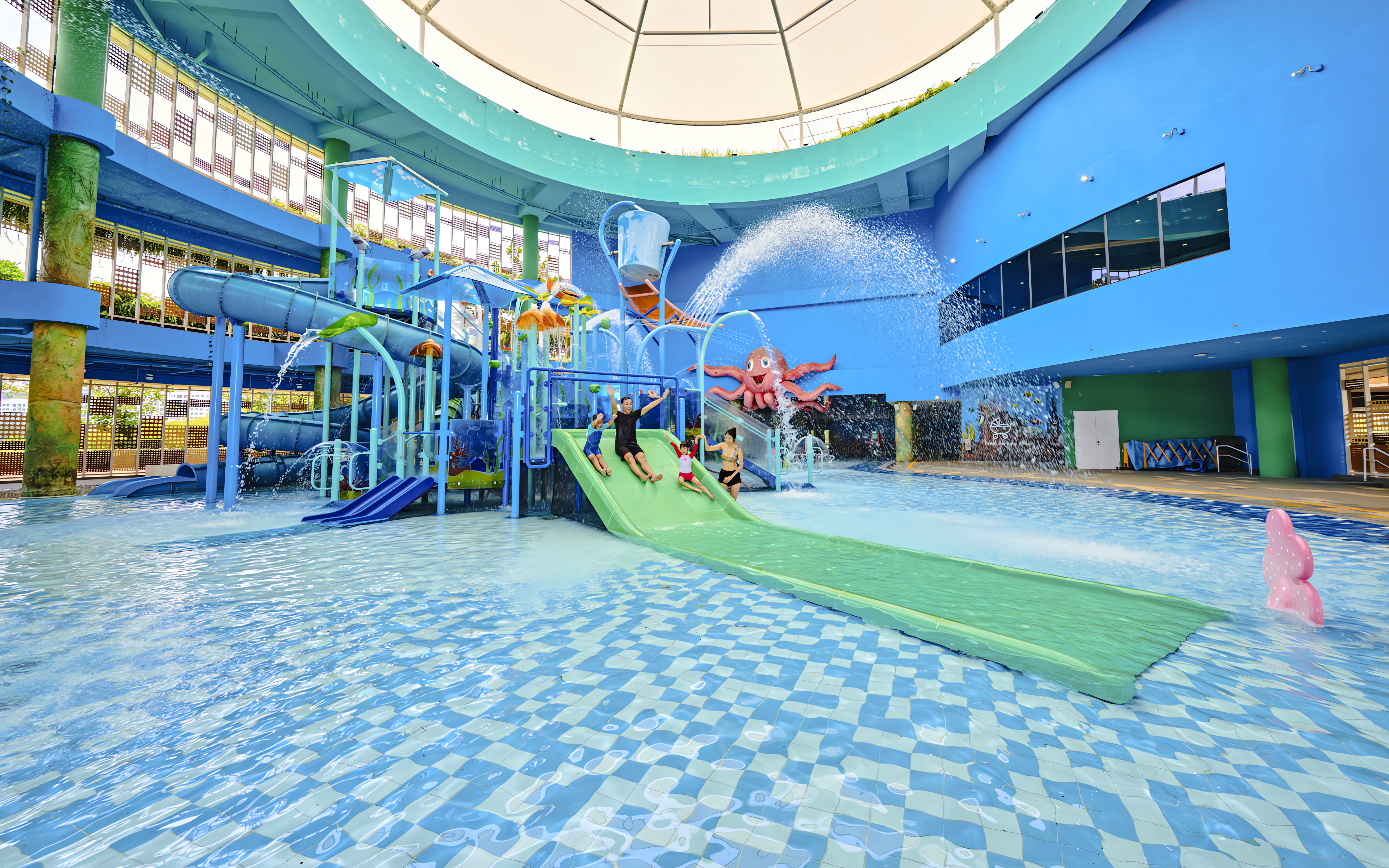 Family enjoying water slide at indoor water park, Singapore.