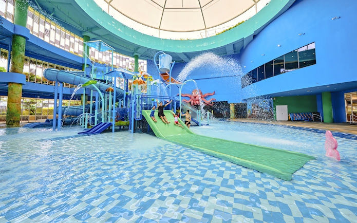 Family enjoying water slide at indoor water park, Singapore.