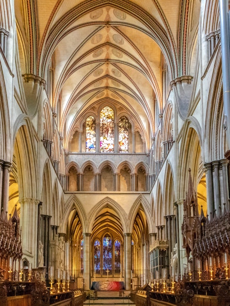 Salisbury Cathedral interior with vaulted ceilings and stained glass windows.
