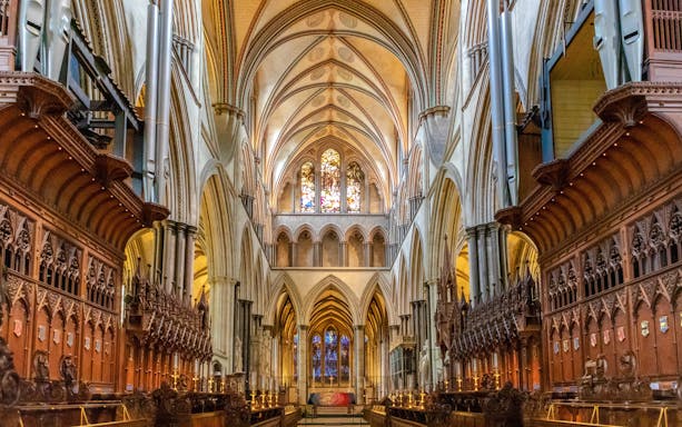 Salisbury Cathedral interior with vaulted ceilings and stained glass windows.