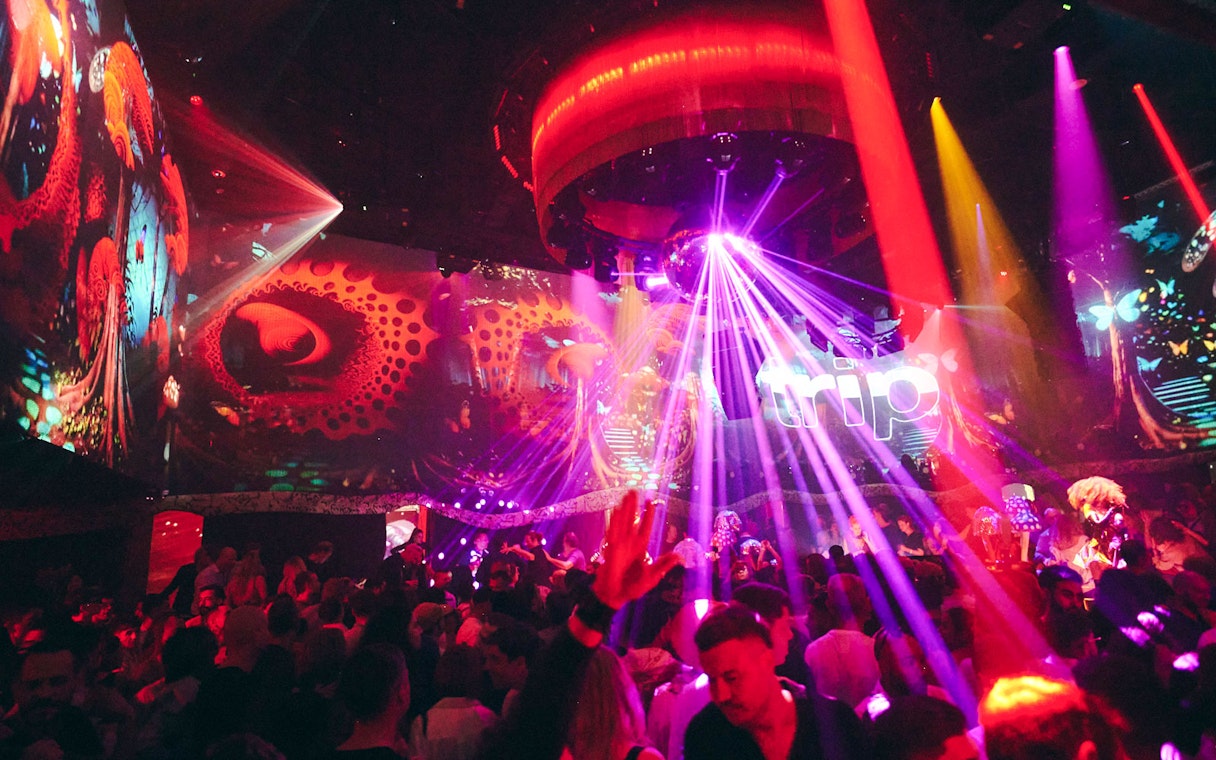 Crowd enjoying vibrant lights and music at TRIP Club Chinois.