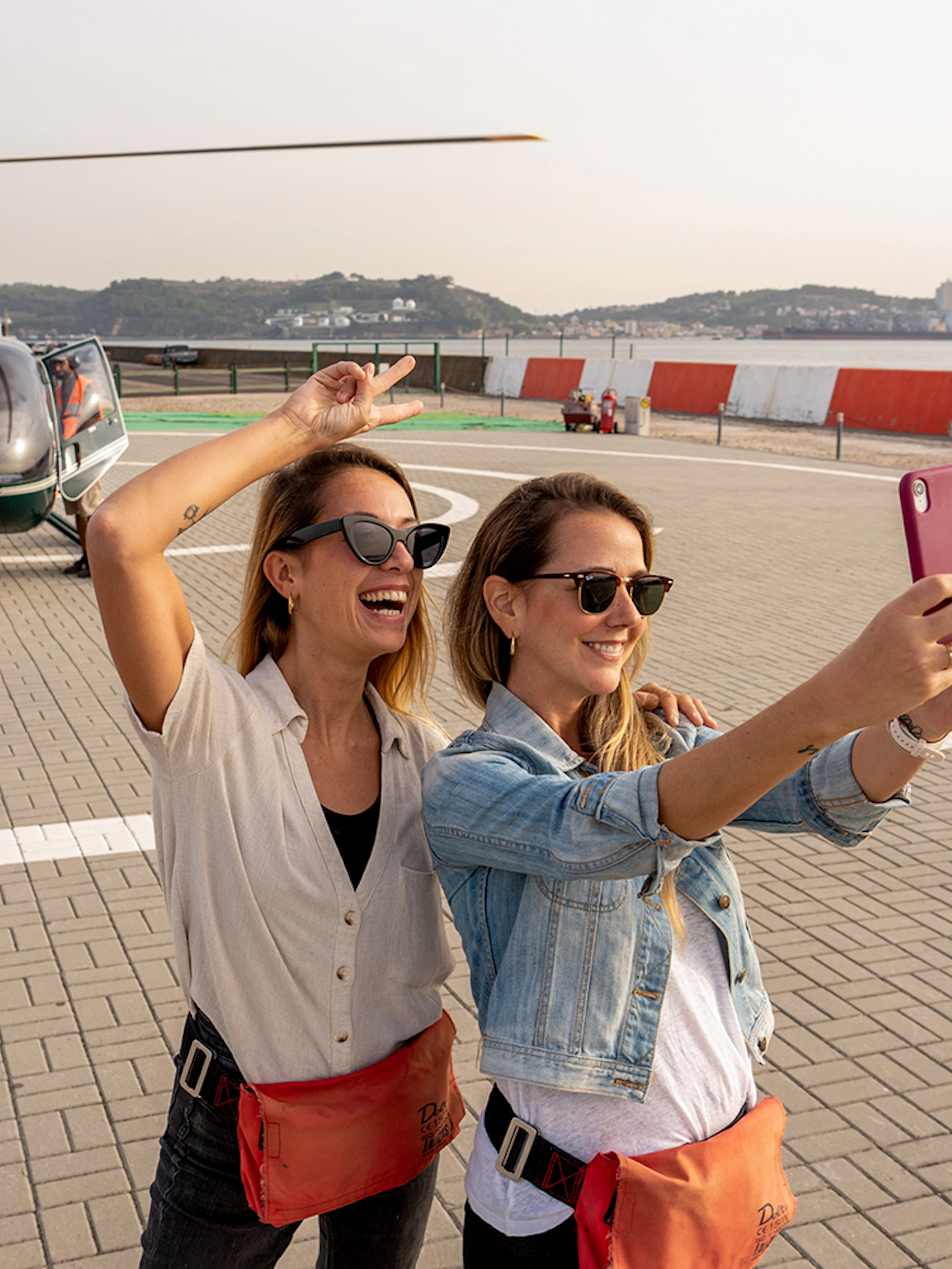 Helicopter on Lisbon helipad with two women taking a selfie before flight.