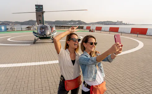 Helicopter on Lisbon helipad with two women taking a selfie before flight.