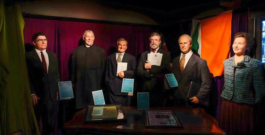 Wax figures of historical figures holding documents at Wax Museum Dublin.