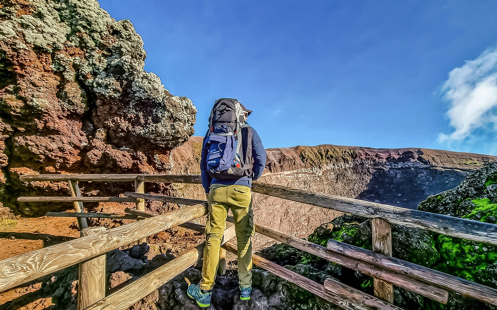 Hiker on Mount Vesuvius trail with view of crater, Italy.