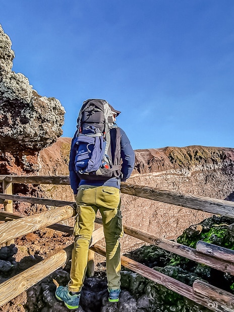 Hiker on Mount Vesuvius trail with view of crater, Italy.