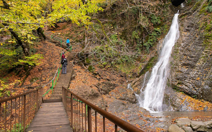 Visitors walking up steps beside Cascade Waterfall in Gabala, Azerbaijan during autumn.