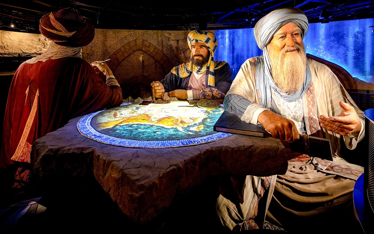 Historical figures discussing a map at Expo City Dubai exhibit.