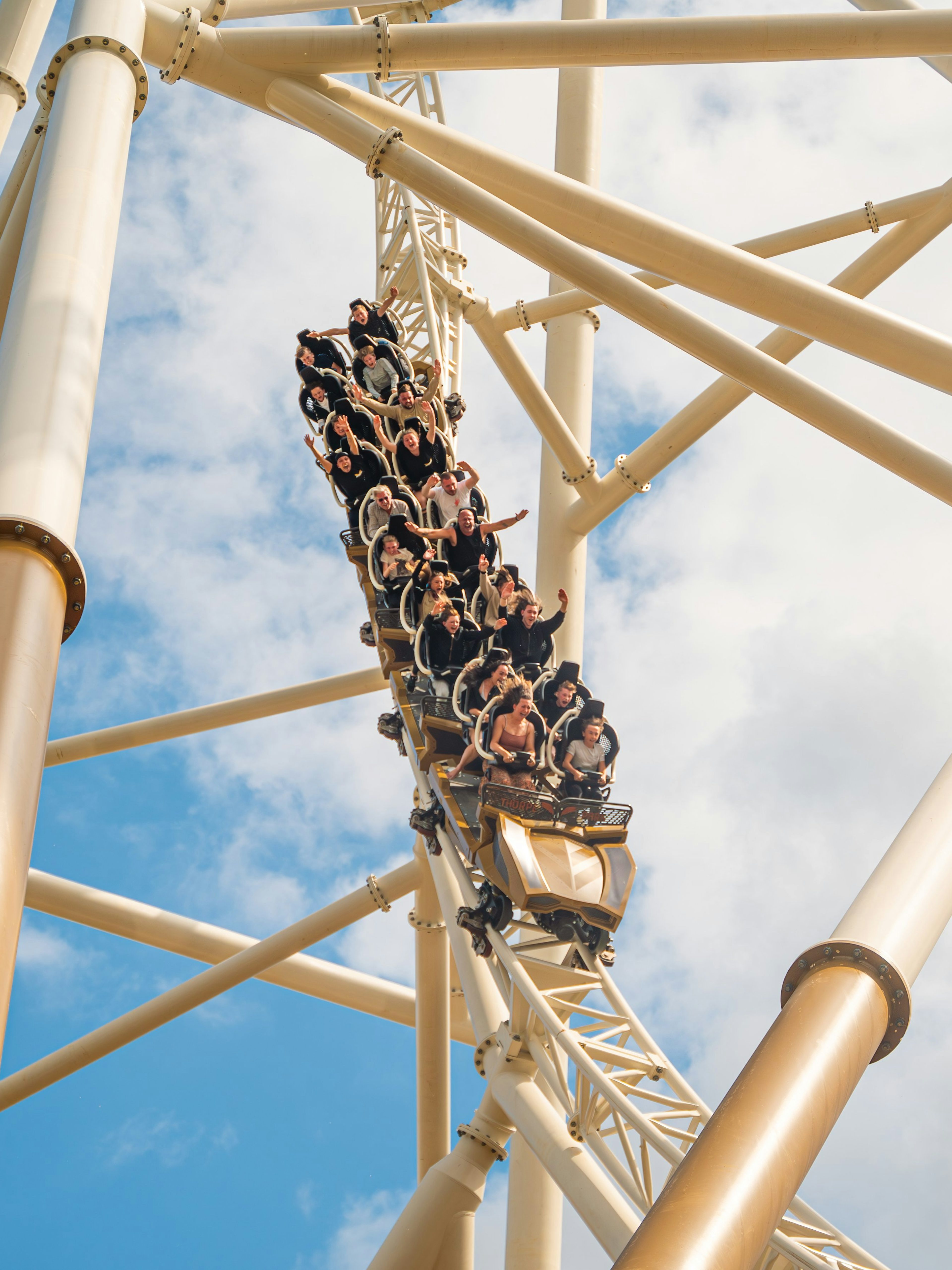 Roller coaster descending at Thorpe Park against blue sky.