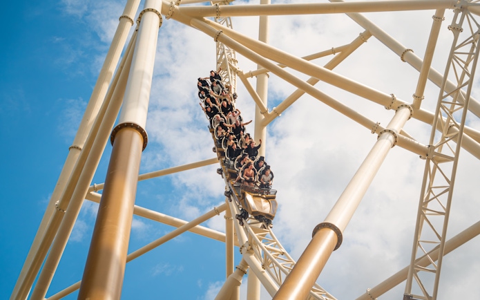 Roller coaster descending at Thorpe Park against blue sky.