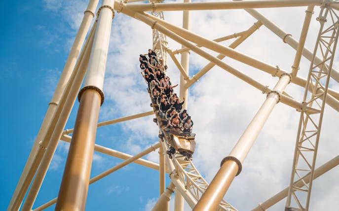 Roller coaster descending at Thorpe Park against blue sky.