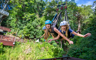 Visitors enjoying a group triple swing at Skypark Cairns amidst lush greenery.