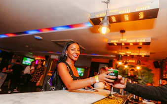 Person enjoying a drink at Lunes de Perreo party in Rio de Janeiro bar.