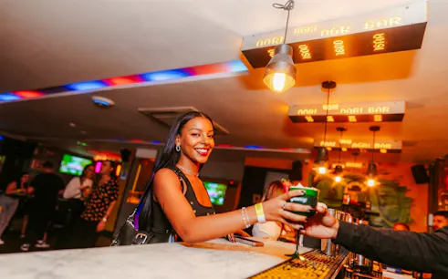 Person enjoying a drink at Lunes de Perreo party in Rio de Janeiro bar.