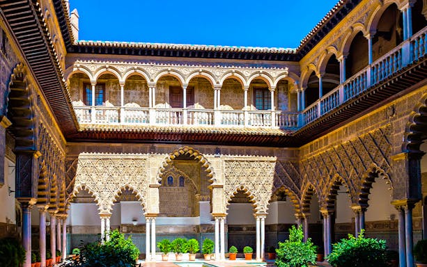 Courtyard of the Alcázar of Seville with intricate arches and detailed stonework.