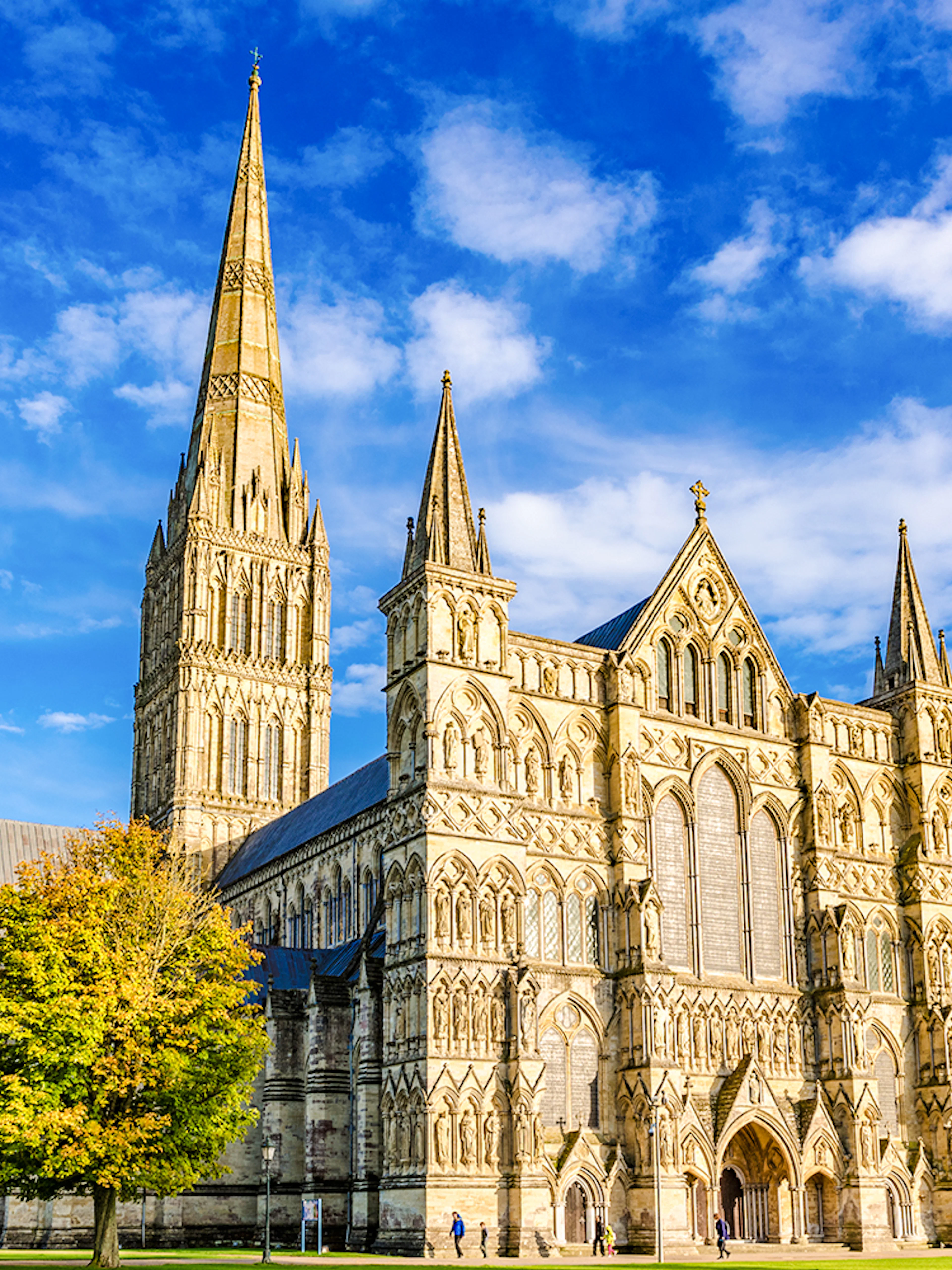 Salisbury Cathedral with its spire and Gothic architecture under a blue sky.