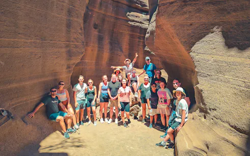Visitors posing inside the narrow, colorful rock formations of Barranco de las Vacas, Agüimes, Gran Canaria.