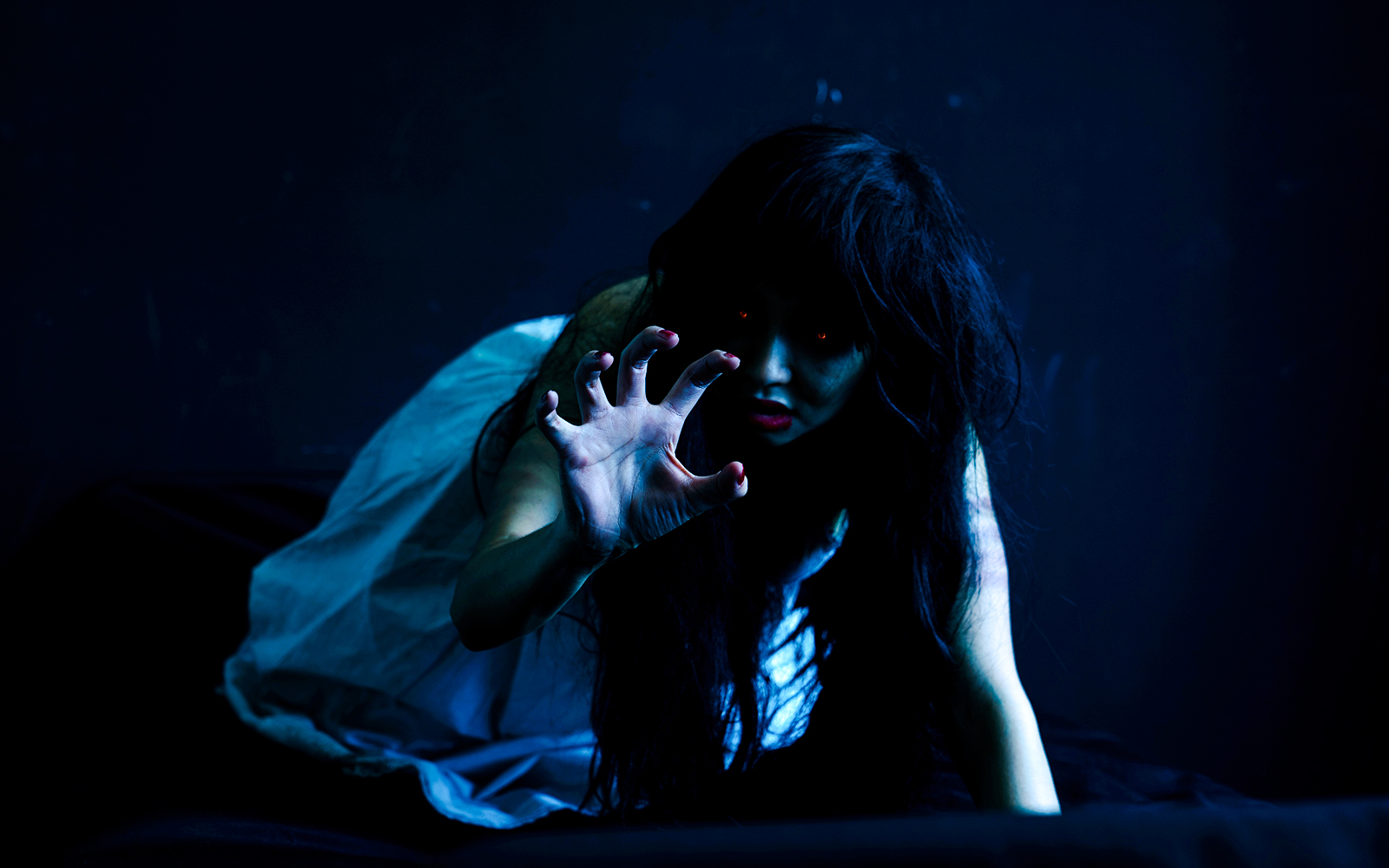 Character reaching out in a dimly lit haunted house.