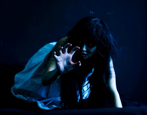 Character reaching out in a dimly lit haunted house.