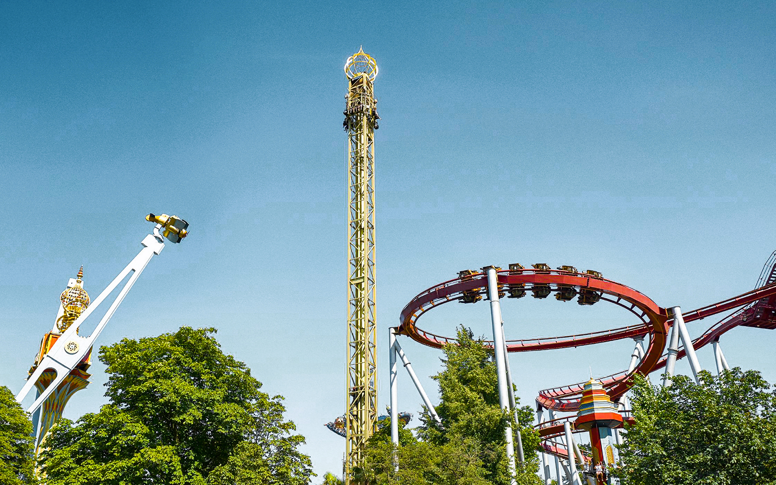 Tivoli Gardens roller coasters and rides against a clear blue sky in Copenhagen.