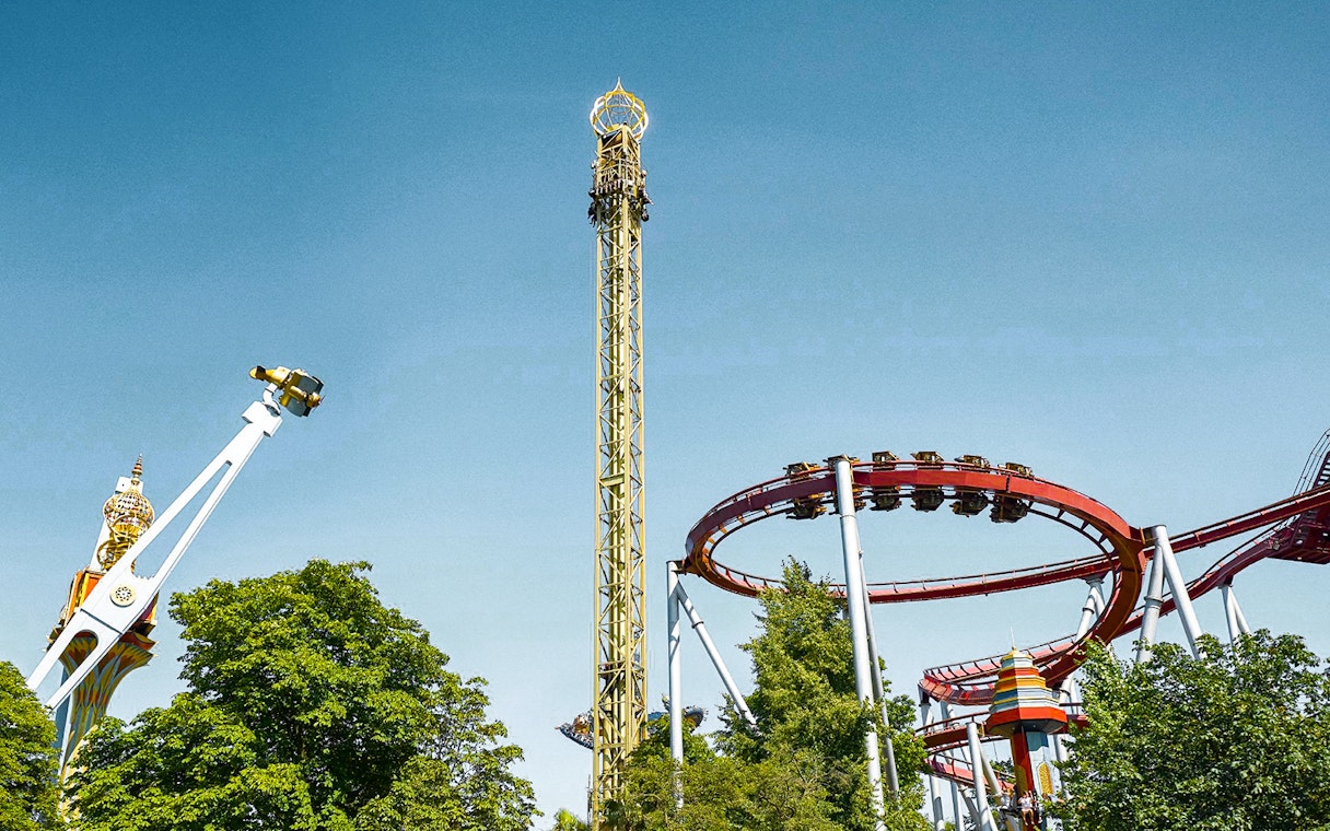 Tivoli Gardens roller coasters and rides against a clear blue sky in Copenhagen.