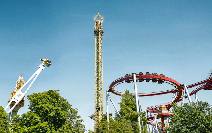 Tivoli Gardens roller coasters and rides against a clear blue sky in Copenhagen.