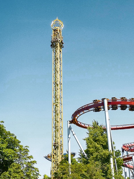 Tivoli Gardens roller coasters and rides against a clear blue sky in Copenhagen.